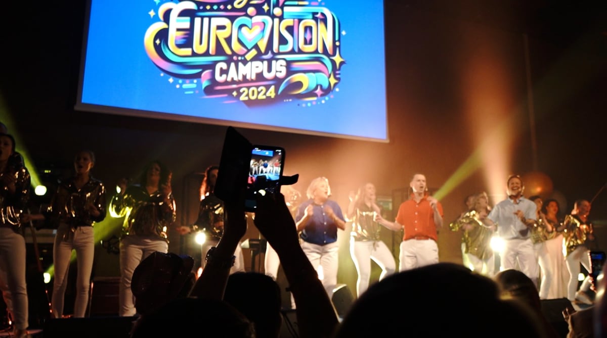 Scen med sångare i guld och vitt under Smile Campus, publik som filmar med mobilen.